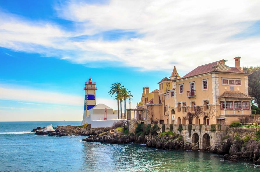 The serene coastal town of Cascais features a picturesque lighthouse and grand, palatial houses along the waterfront. The calm sea and beautiful architecture are often explored by those on Sintra tours