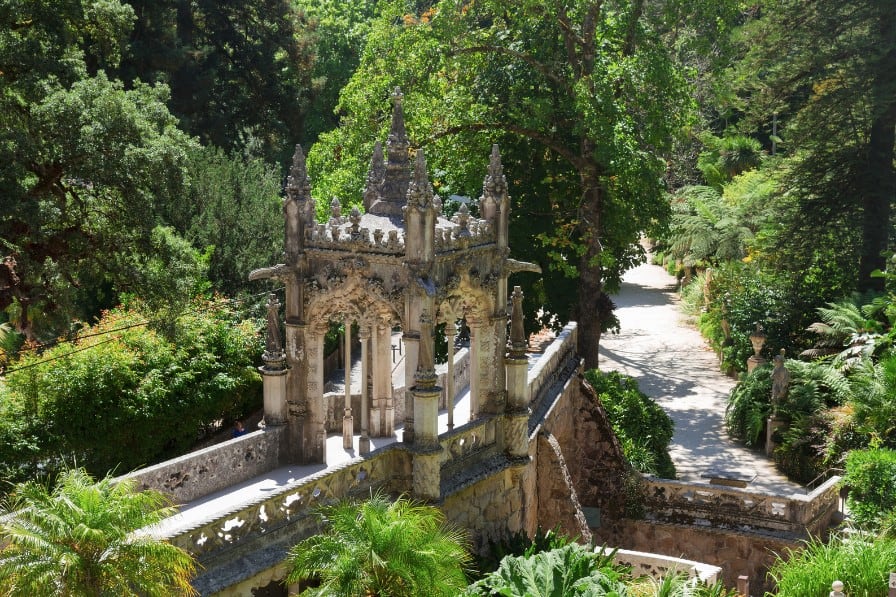 The ornate, gothic-style architecture of Quinta da Regaleira emerges amidst lush, verdant gardens