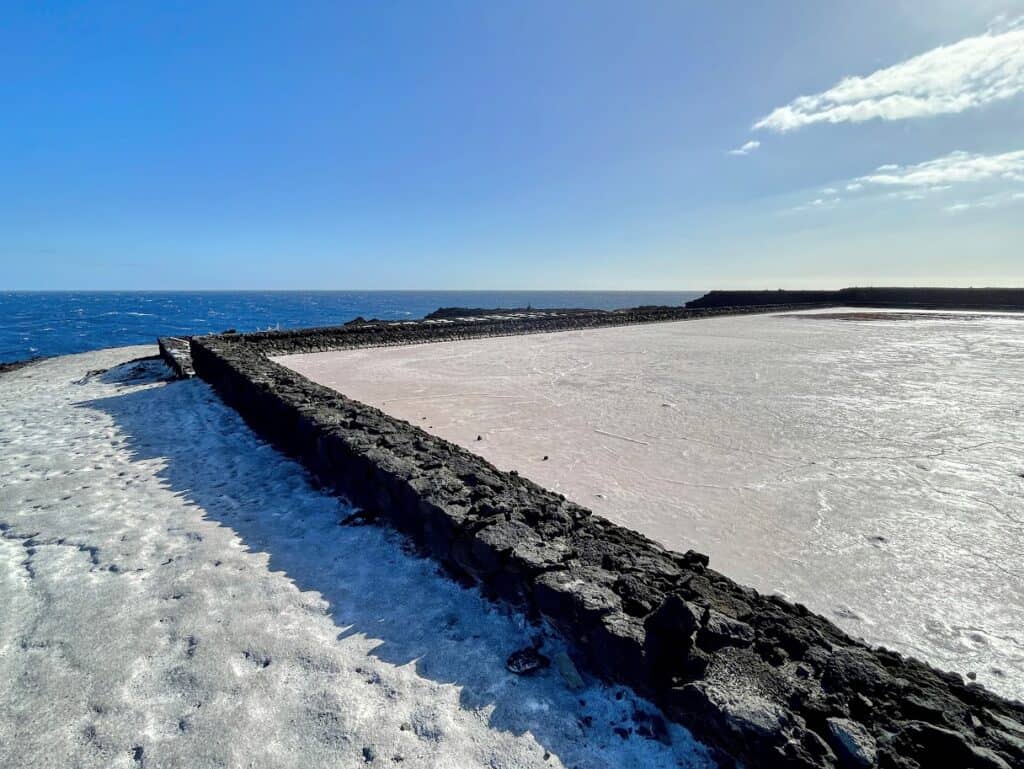 A close-up shot of a salt pan at Fuencaliente La Palma, where the shallow waters are beginning to crystallize under the sun's warmth.