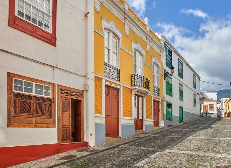 A charming cobblestone street in Santa Cruz de La Palma, lined with traditional Canary Island architecture, showcasing bright facades and wooden balconies that can be seen on a walking tour that's among the delightful things to do in Santa Cruz de la Palma.