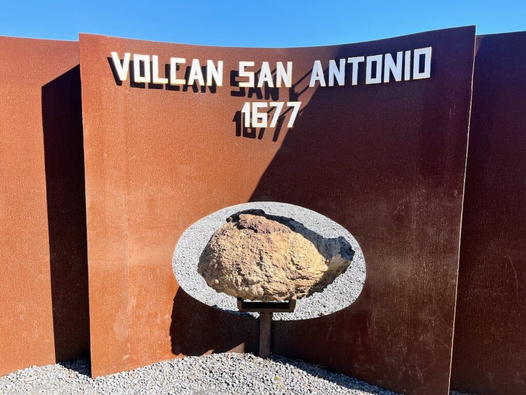 A close-up of the Volcán San Antonio sign with a historical date, set against the rust-colored backdrop, marking the significance of the site for visitors interested in the volcanic history of La Palma.