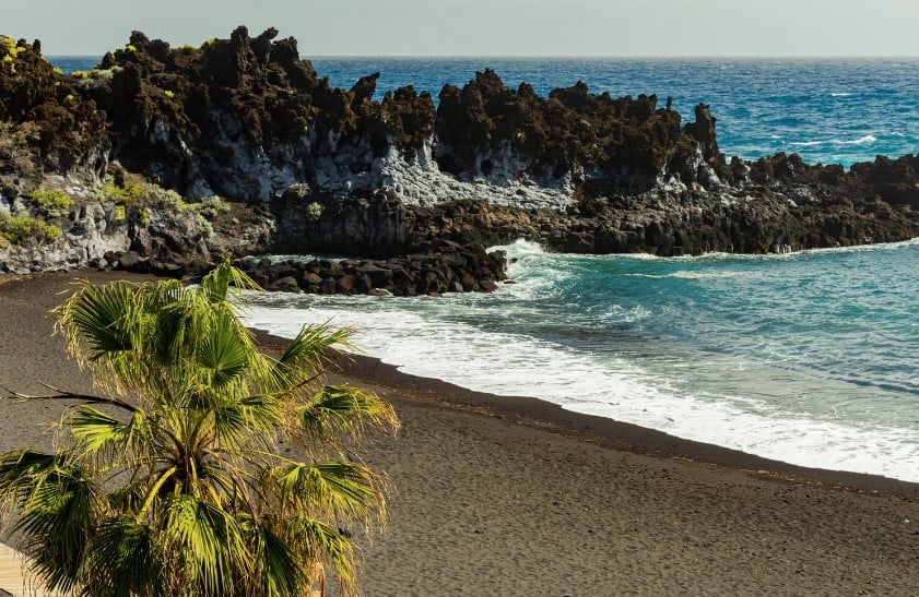 Playa de los Cancajos is a black sand beach with dark rocks lining it when you visit La Palma