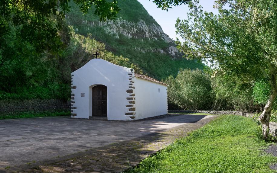 The Ermita San Isidro, a solitary white hermitage against a verdant backdrop, marking a tranquil spot along La Gomera hiking trails.