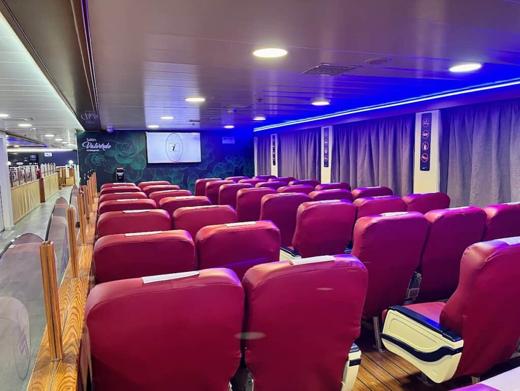 Rows of red seats facing a television screen inside a ferry's lounge area – a comfortable spot for travelers on their way to La Palma.