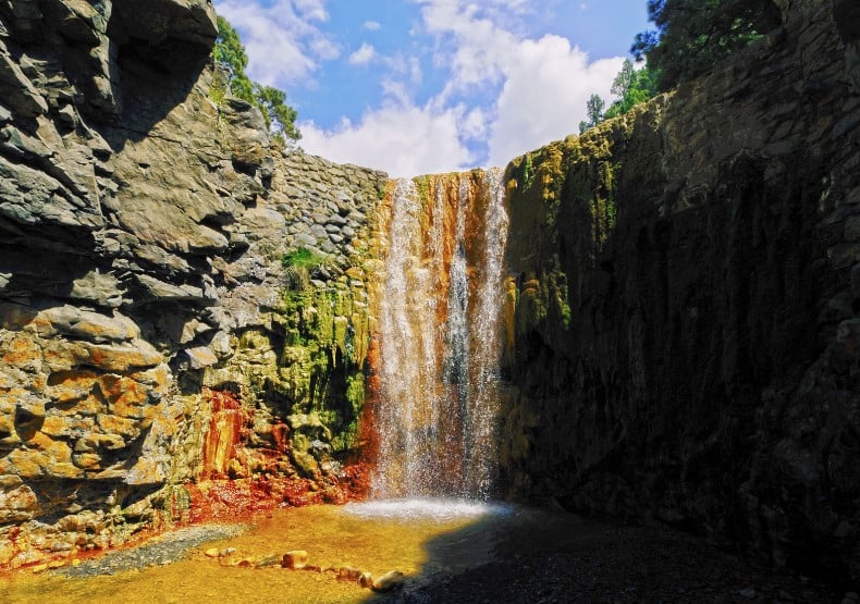 The Waterfall of Colors have all the colors of the rainbow behind the flowing water