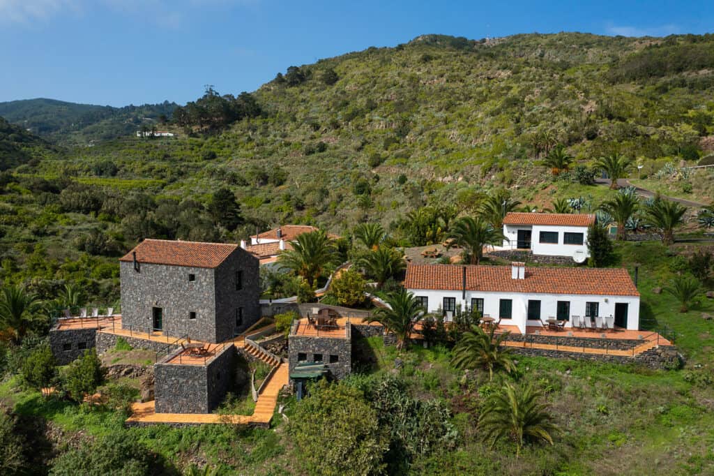 Aerial view of Casa del Chorro, nestled in the lush greenery of La Gomera's mountainside, presenting a unique option for travelers exploring the best hotels in La Gomera for a picturesque and serene stay.