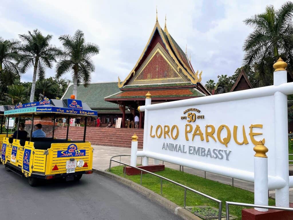 Entrance to Loro Parque Animal Embassy featuring Thai-inspired architecture and a welcoming yellow tram, a family-friendly spot in Tenerife theme parks.