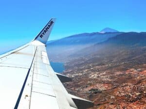 Aerial view of Tenerife's coastline and Mount Teide from an airplane window, highlighting the scenic route of how to get to Tenerife.