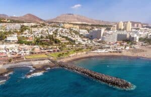 Aerial view of Costa Adeje with hotels and buildings lining the coast, mountains in the background, showcasing hotels in Costa Adeje Tenerife.