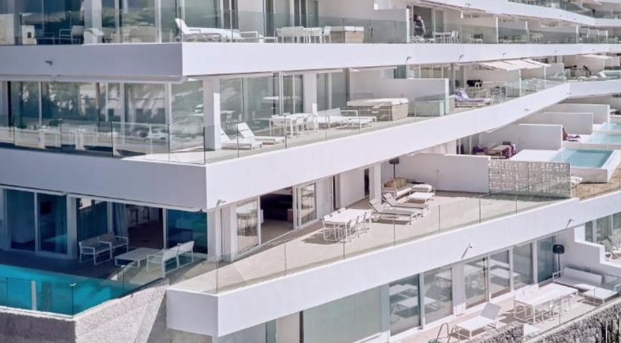 A modern building with spacious terraces, pools, and glass railings at Hotel Baobab Suites, representing luxury hotels in South Tenerife