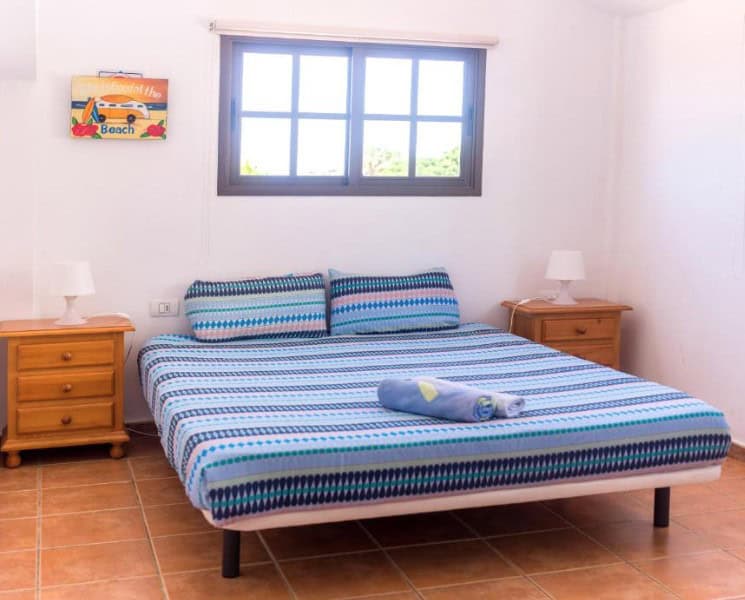 Bright bedroom with a double bed and colorful bedding at La Tortuga Hostel, another example of cheap hotels in South Tenerife.