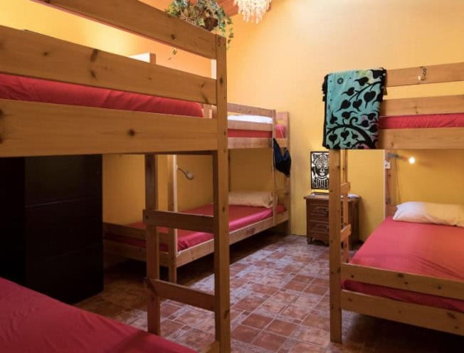 A cozy and vibrant shared dormitory room with bunk beds at one of the best budget hotels in South Tenerife, Los Amigos Hostel.