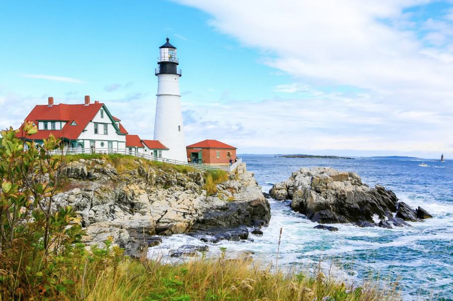 The iconic Portland Head Light with its surrounding rocky coast, a notable landmark on the way from Massachusetts to Maine.