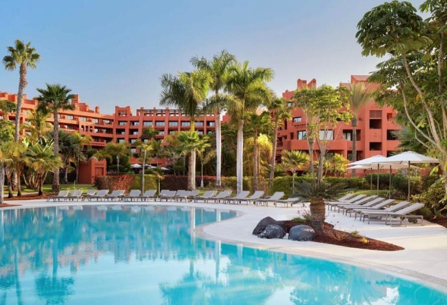 A view of the luxurious pool area at Tivoli La Caleta Resort with palm trees and sun loungers surrounding the pool, representing luxury hotels in Costa Adeje.