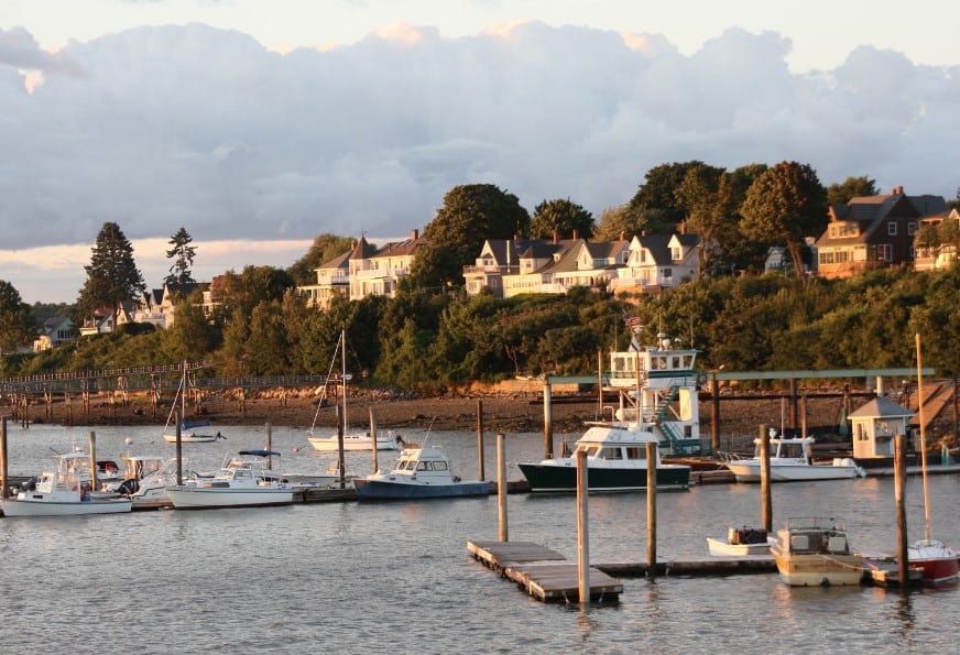 Boats docked at Casco Bay with charming homes in the background, ideal for a perfect weekend in Portland, Maine.
