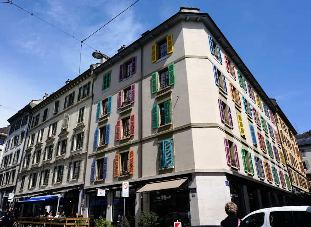 A charming Geneva building with colorful shutters, adding a vibrant touch to the city's architecture. Exploring neighborhoods like this one is a delightful way to spend a day in Geneva.