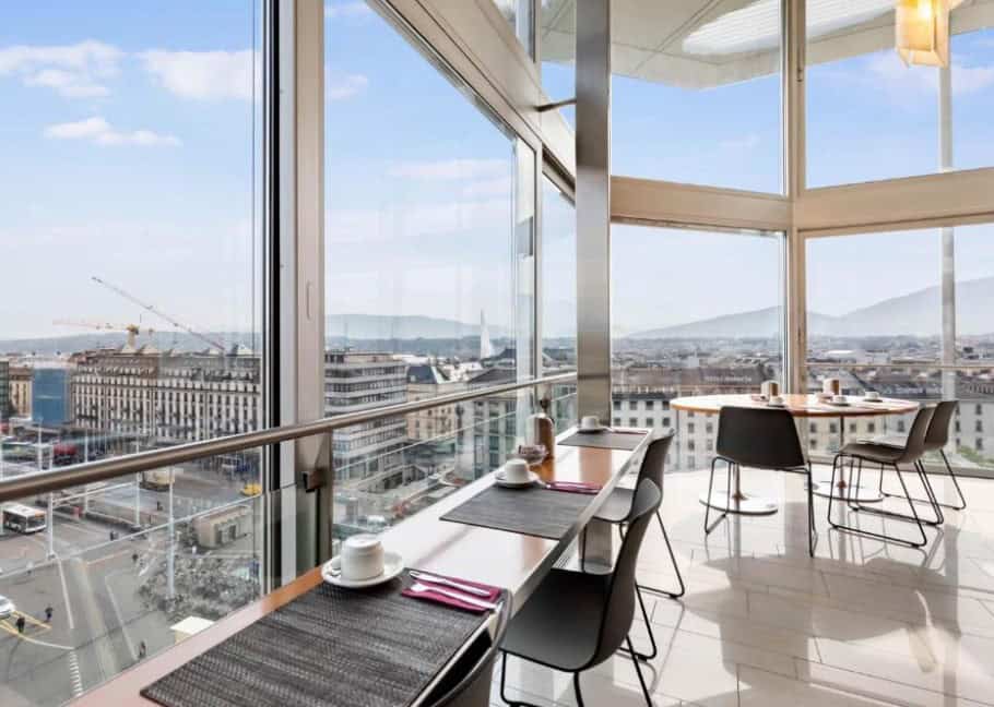 The panoramic breakfast room at Hotel Cornavin Geneva, offering stunning views of the city skyline, perfect for starting the day in a hotel by Geneva train station.