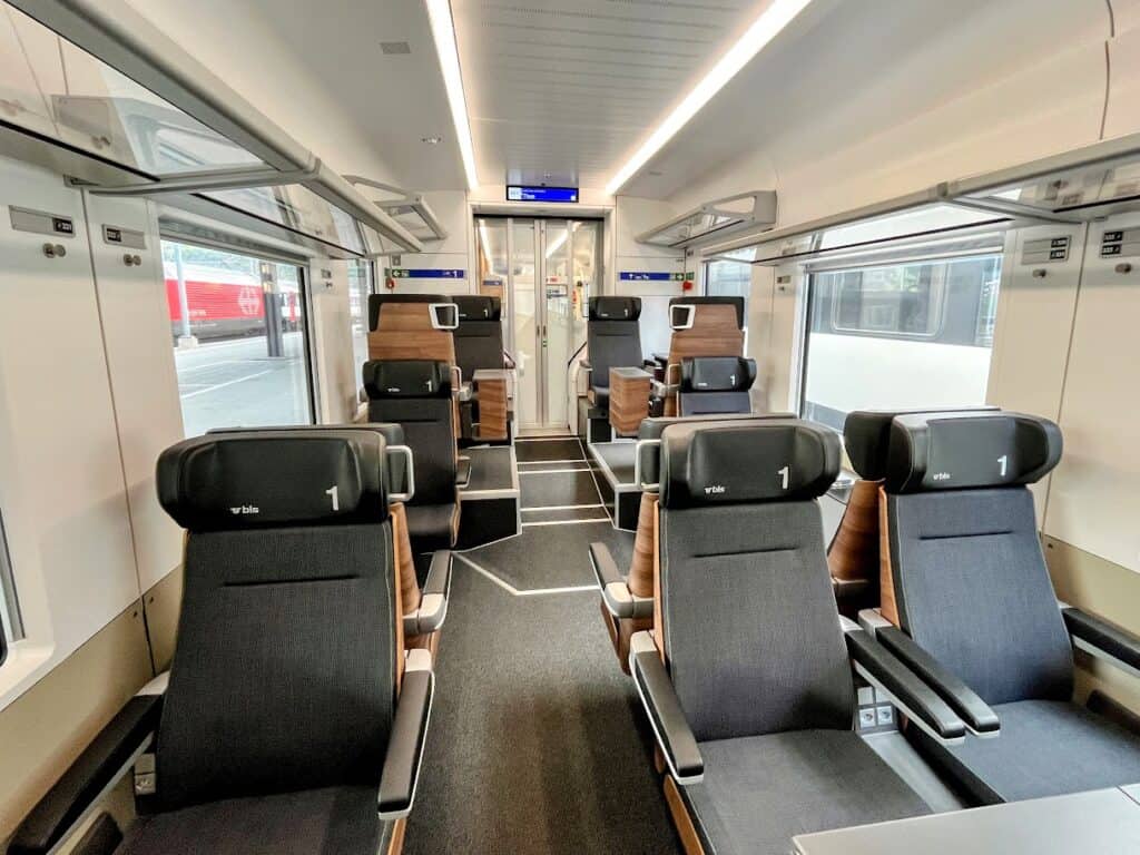 Wide seats and large windows fill a clean and modern first class train carriage in Switzerland. It's a quiet and comfortable way to travel through the country’s scenic routes.