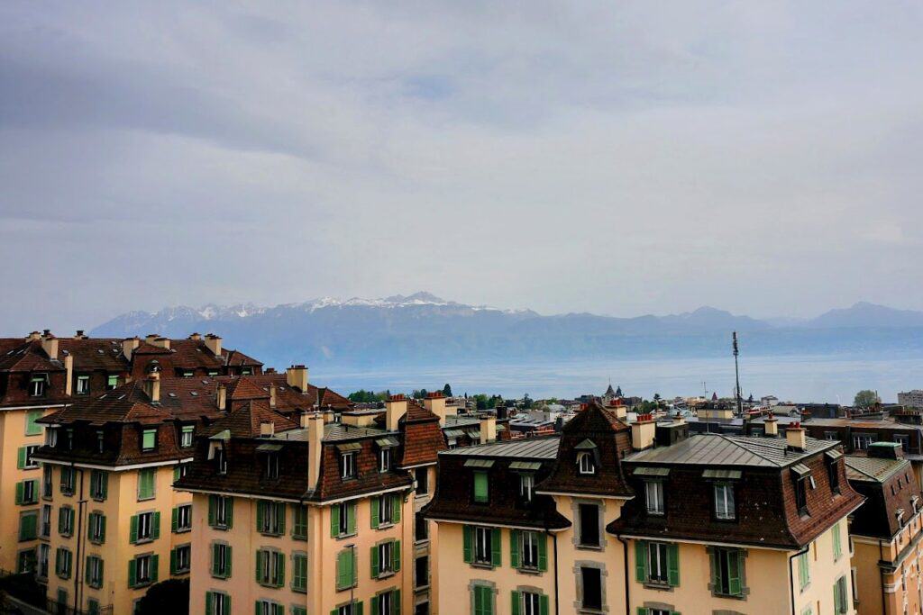 A scenic view of snow-capped mountains towering over the city of Lausanne and Lake Geneva. Lausanne’s hillside location makes it one of the best places to visit around Lake Geneva, Switzerland for incredible views.