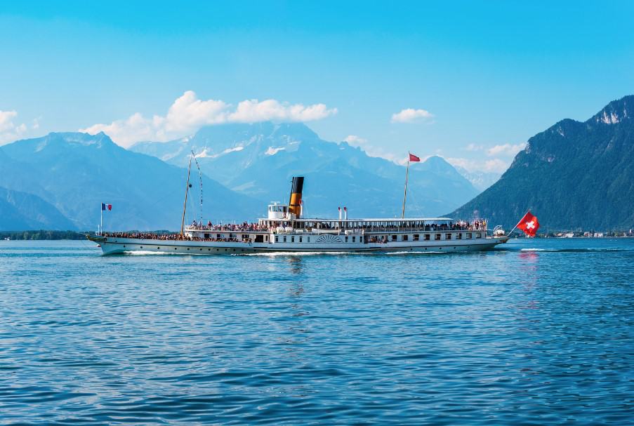 A historic steamboat sailing on Lake Geneva with the Swiss and French Alps in the background. This image highlights a classic option for Lake Geneva Switzerland boat tours, perfect for travelers wanting to experience the scenic charm of the region's majestic mountains.