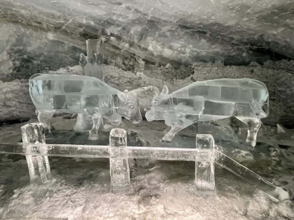 Intricate ice sculptures within the Glacier Palace, featuring detailed carvings of animals and landscapes, shimmering under cool lighting in the ice cave.