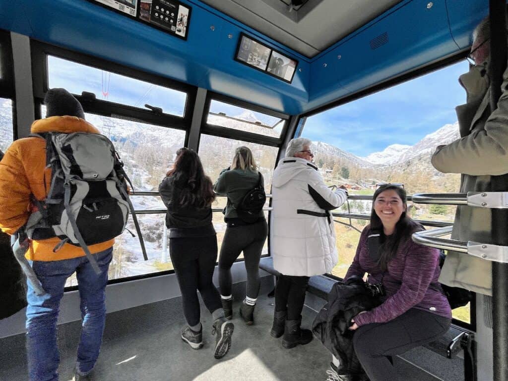 Passengers ride the gondola lift toward the snowy peaks above Zermatt, with wide windows giving views of the mountains. Taking this scenic ride is one of the most enjoyable summer activities in Zermatt, especially when the skies are clear.