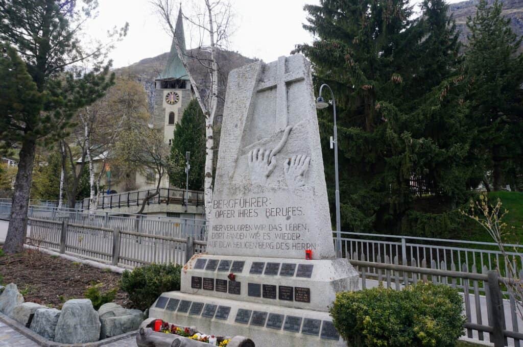 A stone monument stands near the church in Zermatt, honoring mountain guides who lost their lives in the Alps.
