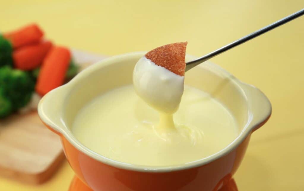 A hearty spread of bread cubes and vegetables for dipping in smooth, melted cheese fondue, perfect for a classic Swiss dining experience.